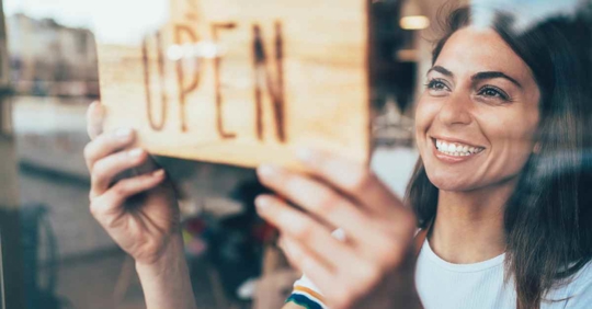 A woman flipping an "Open" sign at her business