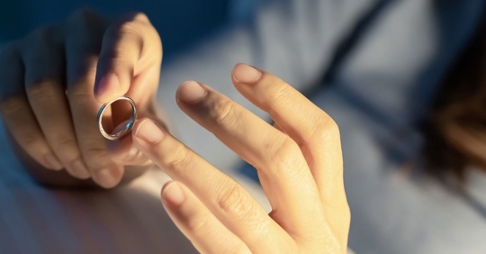 person taking wedding ring off finger
