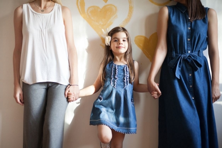 Little girl holding both of her mom's hands