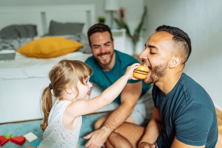Two dads playing with daughter