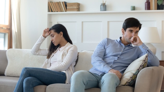 man and woman sitting on couch unhappy with each other